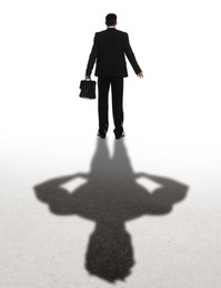 Businessman and shadow of strong muscular man behind him on white background. Concept of inner strength