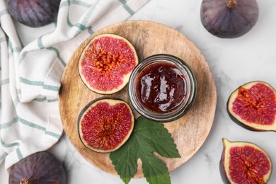 Photo of Glass jar of tasty sweet fig jam and fruits on white marble table, flat lay