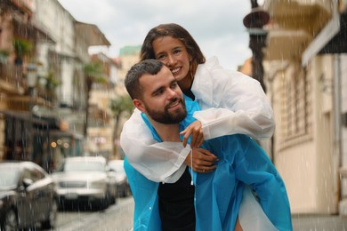 Young couple in raincoats enjoying time together on city street