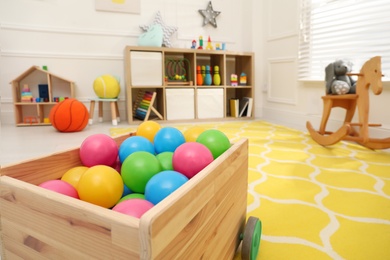 Photo of Closeup view of toy car trailer with colorful balls in child's room, space for text. Interior design
