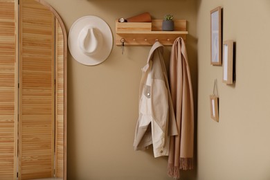 Hallway interior with stylish accessories and wooden hanger for keys on beige wall