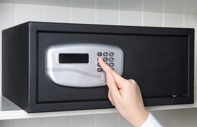 Woman opening steel safe with electronic lock, closeup