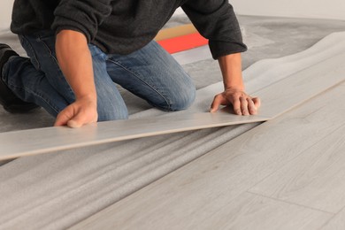 Photo of Professional worker installing new laminate flooring, closeup