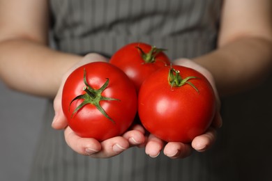 Photo of Woman with ripe tomatoes on grey background, closeup
