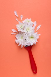 Creative flat lay composition with paint brush and white chrysanthemum flowers on coral background