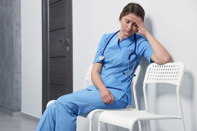 Photo of Exhausted doctor resting on chair in hospital