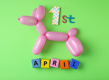 Balloon animal and phrase 1st APRIL on green background, flat lay. Fool's day
