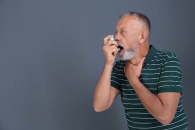Man using asthma inhaler on color background with space for text