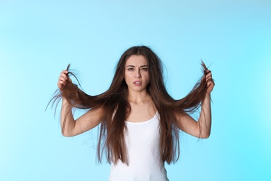 Photo of Emotional woman with damaged hair on color background. Split ends