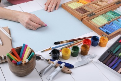 Artist drawing with chalk pastel at white wooden table, closeup