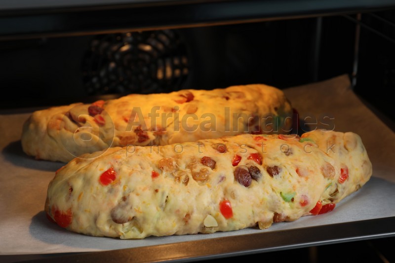 Raw homemade Stollens with candied fruits and nuts on baking tray in oven, closeup. Traditional German Christmas bread