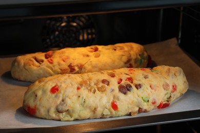 Raw homemade Stollens with candied fruits and nuts on baking tray in oven, closeup. Traditional German Christmas bread