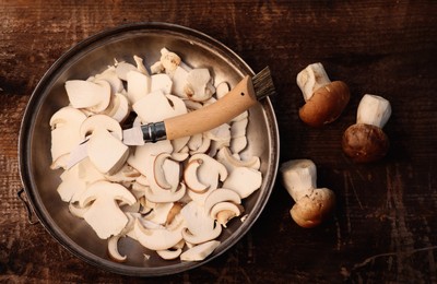 Knife, cut and whole mushrooms on wooden table, flat lay