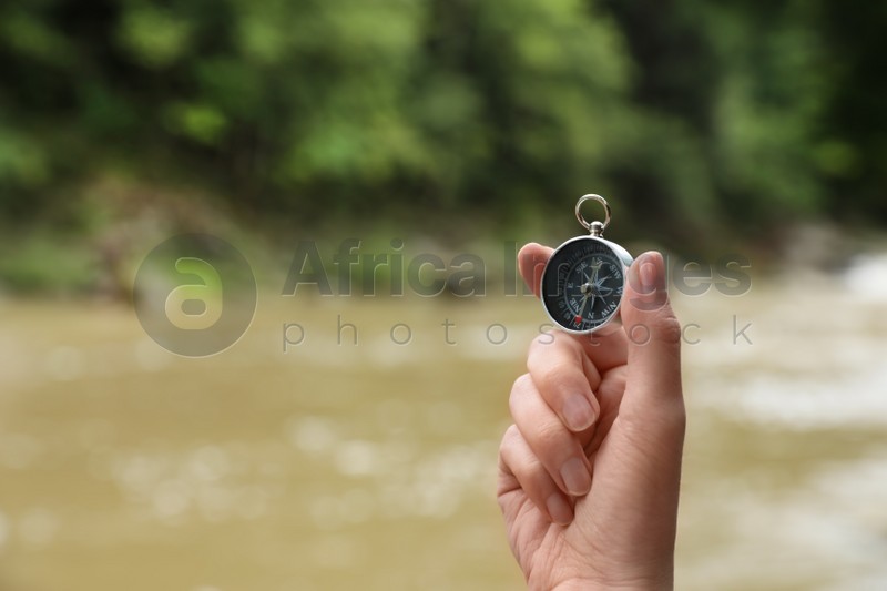 Traveler searching direction with compass in wilderness, closeup. Space for text