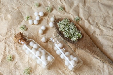 Homeopathic remedy in bottles and spoon on wrinkled paper