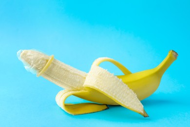 Banana with condom on light blue background. Safe sex concept