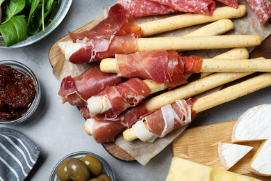 Tasty prosciutto served on light grey table, flat lay