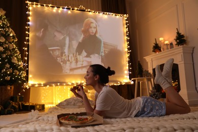 MYKOLAIV, UKRAINE - DECEMBER 24, 2020: Woman watching The Queen's Gambit series via video projector in room. Cozy winter holidays atmosphere