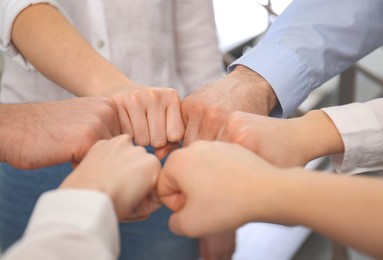 People holding fists together in office, closeup