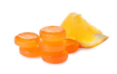 Many cough drops and slice of orange on white background