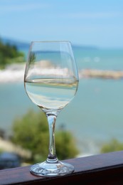 Glass with wine on railing near sea