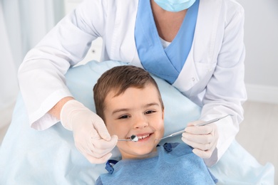 Dentist examining cute boy's teeth in modern clinic