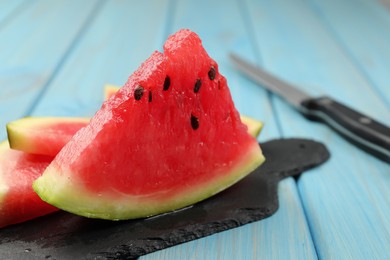 Slate board with slices of juicy watermelon on light blue wooden table, closeup