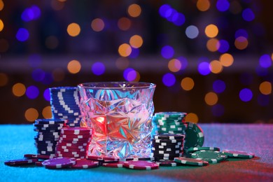 Alcohol drink and casino chips on table against blurred lights