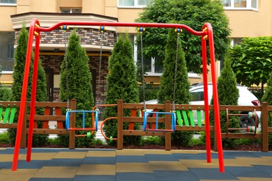 Empty outdoor children's playground with swings in residential area