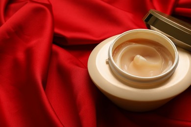 Open jar of hair care cosmetic product on red fabric, closeup. Space for text