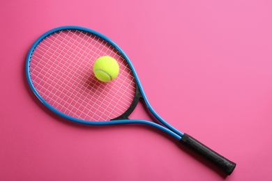 Tennis racket and ball on pink background, top view. Sports equipment