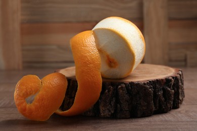 Photo of Peeled fresh orange with zest preparing for drying on wooden table