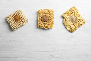 Flat lay composition with different quick cooking noodles on wooden background. Space for text