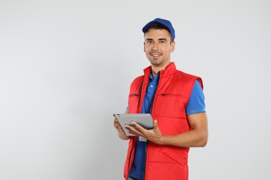 Happy young courier with tablet on white background
