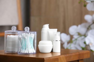 Cotton pads and swabs near cosmetic products on wooden stool in room