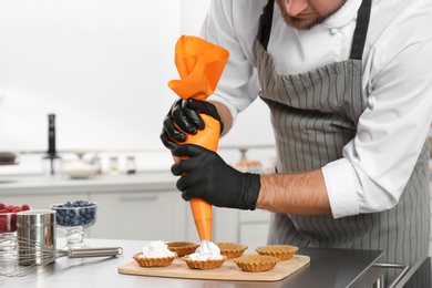 Pastry chef preparing desserts at table in kitchen, closeup
