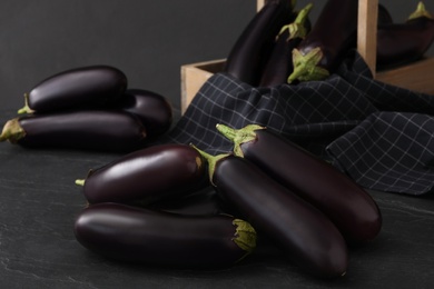Many raw ripe eggplants on black table