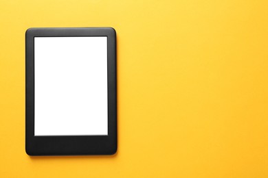 Modern e-book reader with blank screen on orange background, top view. Space for text