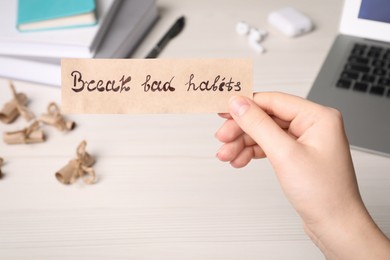 Photo of Woman holding paper note with phrase Break Bad Habits over white table, closeup