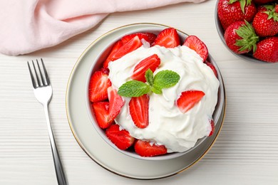 Delicious strawberries with whipped cream served on white wooden table, flat lay