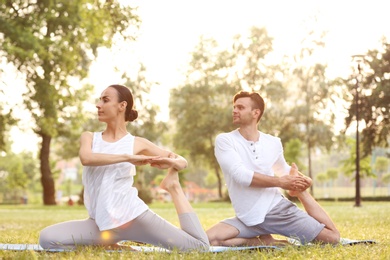 Young couple practicing yoga in park at morning