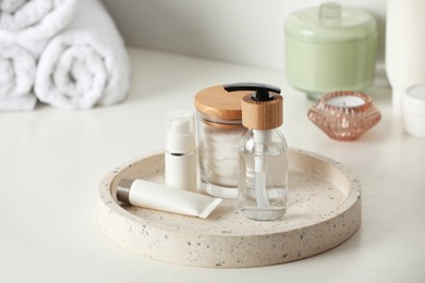 Tray with dispenser bottle and cosmetic products on white table in bathroom