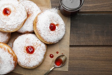 Many delicious donuts with jelly and powdered sugar on wooden table, flat lay. Space for text