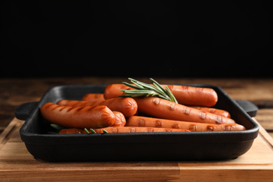 Delicious grilled sausages with rosemary on wooden table