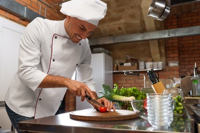 Professional chef cutting fresh tomato in restaurant kitchen