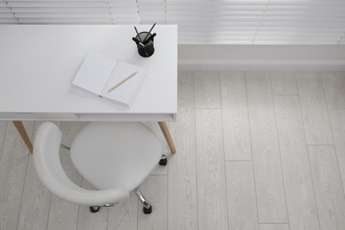 Stylish workplace with white desk and comfortable chair near window indoors, above view. Interior design