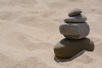Stack of stones on beautiful sandy beach, space for text