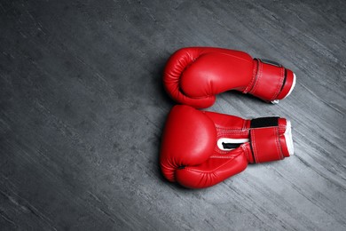 Pair of red boxing gloves on grey stone background, flat lay. Space for text