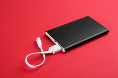 Modern portable charger with cable on red background