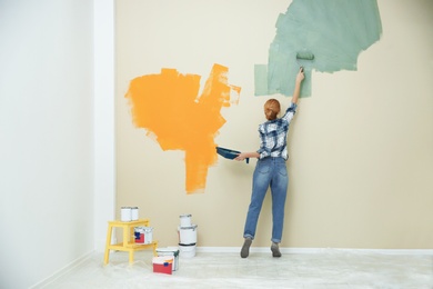 Woman painting wall indoors, space for text. Home repair